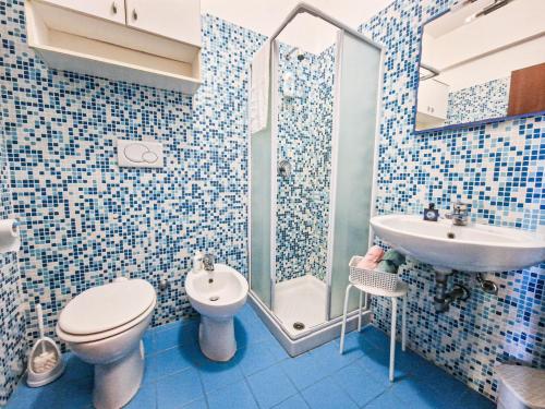 a blue tiled bathroom with a toilet and a sink at Mono Le Lecce 25 b in Capoliveri