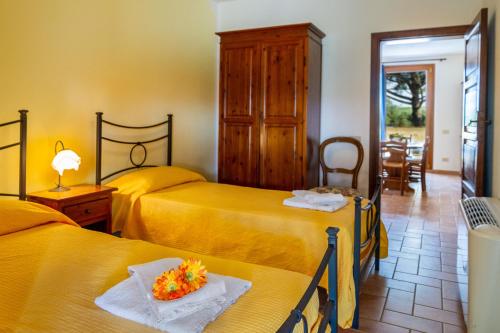 a hotel room with two beds with flowers on a table at Capracotta - Sole in Montemassi