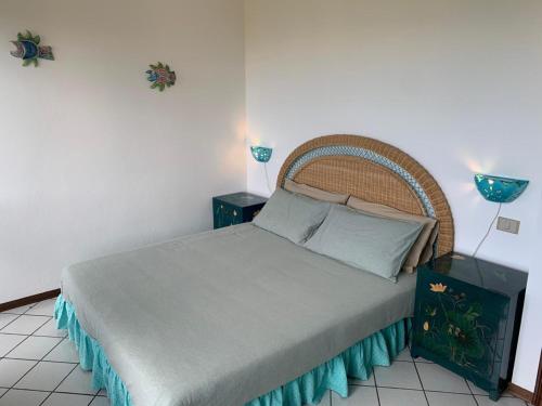 a bedroom with a bed with a wicker headboard at Villino Le Ortensie in Stintino