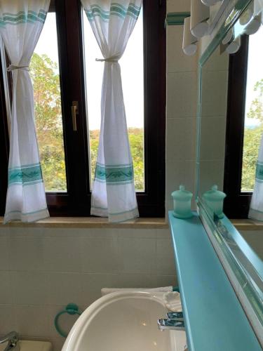 a bathroom with a sink and two windows at Villino Le Ortensie in Stintino
