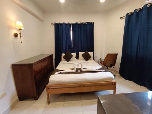 a bedroom with two beds with blue curtains at 1 Bhk apartment kyle garden baga beech in Baga