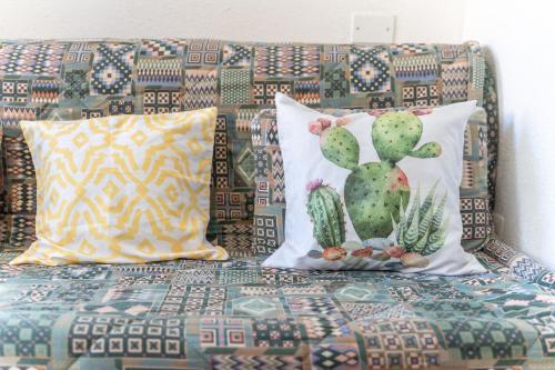 a couch with two pillows and a cactus on it at Sea Shell Isola Rossa in Isola Rossa
