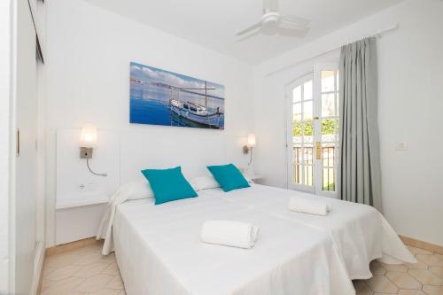 a white bedroom with a large bed with blue pillows at Girasol Garden Superior 2 in Menorca