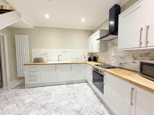 a white kitchen with white cabinets and a sink at The Hideout in Southampton