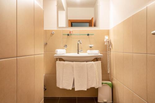 a bathroom with a sink and a mirror and towels at Sabina Dolomites Joch in Alpe di Siusi