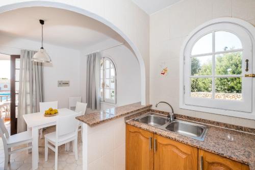 a kitchen with a sink and a table with chairs at Girasol Garden Superior 2 in Menorca