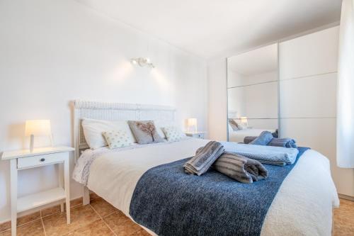 a white bedroom with a large bed with a blue blanket at Wonderful in Can Picafort