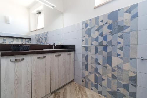 a kitchen with a sink and a tile wall at Appartamento Blu in Dorgali
