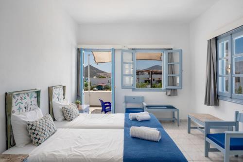a room with a bed and a table and windows at Pico Bello Patmos 16 in Patmos