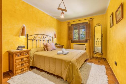 a bedroom with yellow walls and a bed and a dresser at Cortijo Jiménez in Pitres