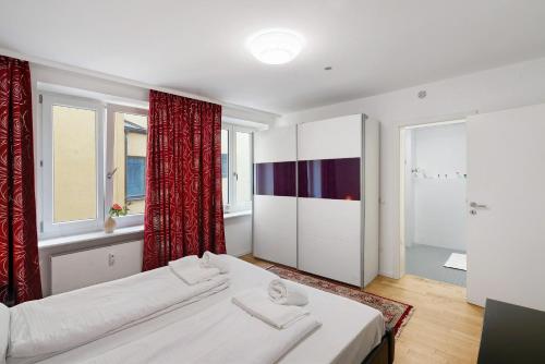 a bedroom with a white bed and red curtains at Aldars Urban Grand Suite No.15 in Munich