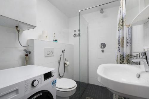 a white bathroom with a toilet and a sink at Aldars Urban Grand Suite No.15 in Munich