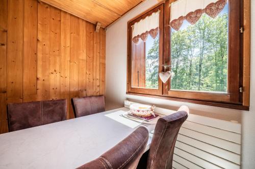 a dining room with a table and chairs and a window at Au Rêve Savoyard 6 - 4 personnes in Morillon