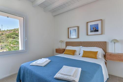 a bedroom with a blue and white bed with a window at Casa Azzurrina Mare in Seccheto