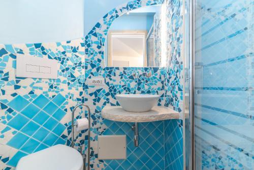 a blue tiled bathroom with a sink and a mirror at Mavi Primo Piano in Palau