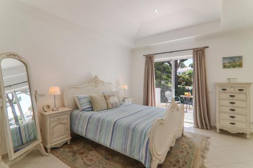 a bedroom with a bed and a dresser and a mirror at Villa Karon in Almancil