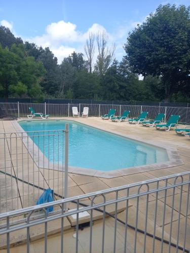 a swimming pool with chairs and a fence at Camping Sainte-Jalle in Sainte-Jalle