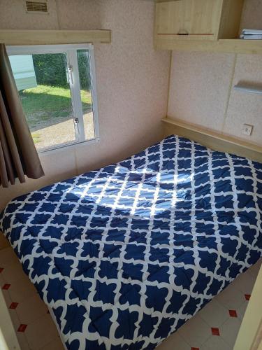 a blue and white bed in a room with a window at Camping Sainte-Jalle in Sainte-Jalle