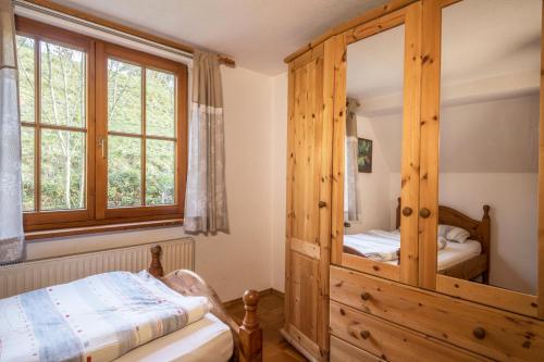 a bedroom with a wooden cabinet with a mirror at Ferienwohnung Achraintal 1 in Lindau