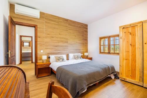 a bedroom with a bed and a wooden wall at Sa Caseta Biniali in Biniali