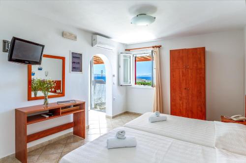 a large bedroom with two beds and a television at Anemologio 202 Studio Tinos in Agios Ioannis