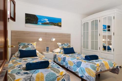 a bedroom with two beds with blue pillows at Casa Playa Palmeras in Puerto del Carmen
