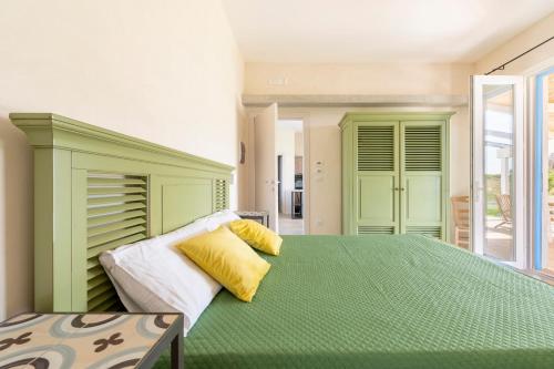 a bedroom with a large green bed with yellow pillows at Casale 50 Elegante Villa a Otranto in Otranto