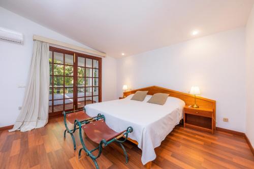 a white bedroom with a bed and a window at Villa Beach Palmitos in Can Picafort
