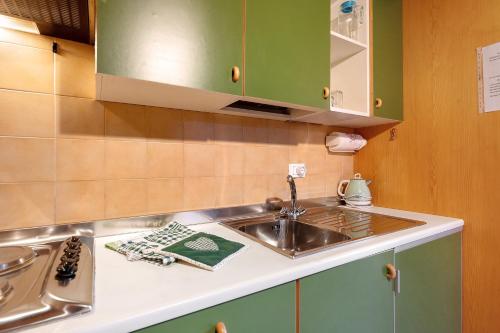 a kitchen with green cabinets and a sink at Casa Serena in Cavalese