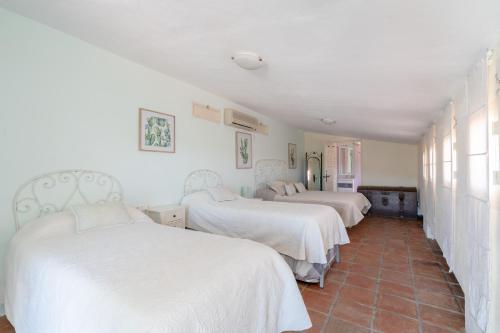 a bedroom with three beds with white sheets and a tile floor at Finca Colica in Cómpeta