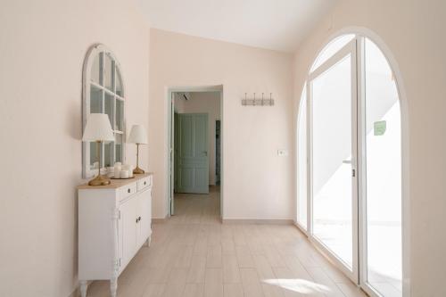 a white room with a hallway with a mirror and a dresser at Finca Colica in Cómpeta