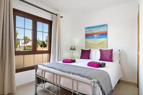 a bedroom with a bed with purple pillows and a window at Villa Jeamir I in Playa Blanca