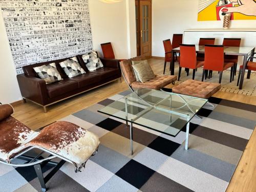 a living room with a glass table and chairs at Atlantic Lodge, 1ª linha de praia! in Costa da Caparica