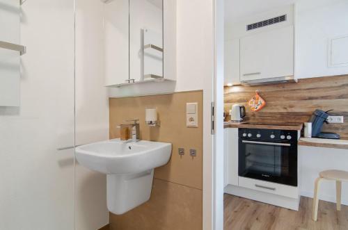 a white bathroom with a sink and a stove at Ferienwohnung Gartenblick in Herdwangen-Schönach