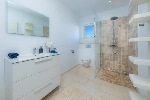 a white bathroom with a sink and a shower at Villa Amarador in Santanyi