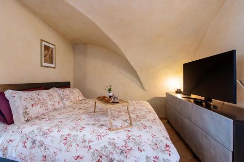 a bedroom with a bed with a tv and a table at Le Volte - Lago D'Iseo in Pisogne
