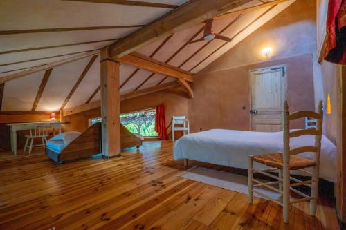 a bedroom with a bed and a chair in a room at Gîte Écologique - Le Nid des Anges in Saint-André-Lachamp