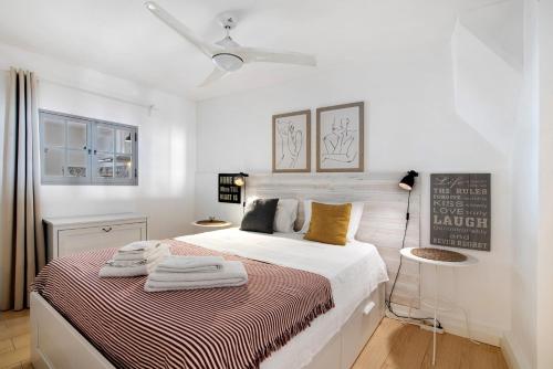 a white bedroom with a bed with towels on it at Casa Amarela in Tavira