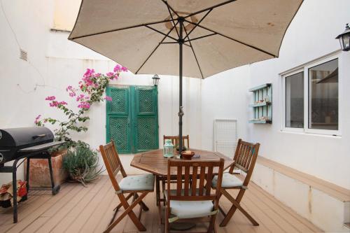 a wooden table with chairs and an umbrella at Casa Amarela in Tavira