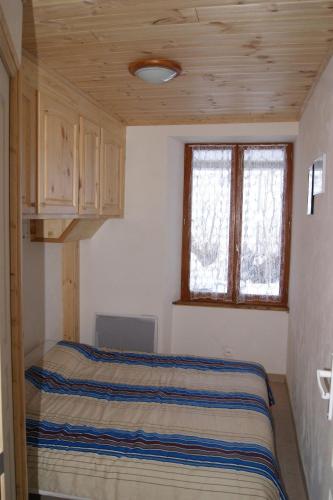 a small bedroom with a bed and two windows at Appartement la Cascade in Allos