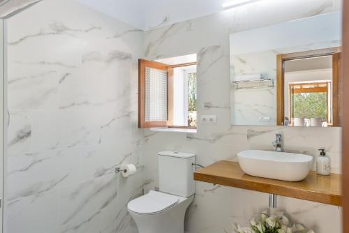 a white bathroom with a sink and a toilet at Ca Ses Celleres in La Mola