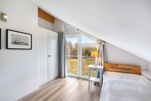 a white bedroom with a bed and a window at Wildrosenhaus in Kosel