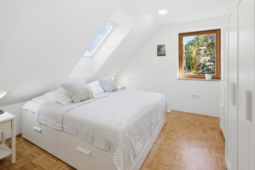 a white bedroom with a bed and a window at Mini Trenta in Soča