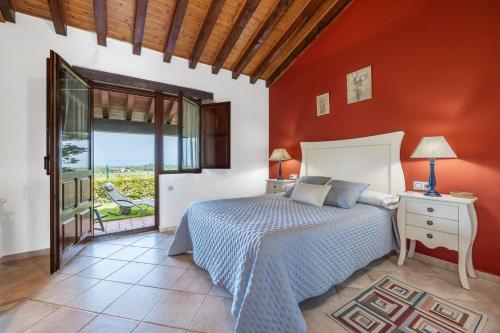 a bedroom with a bed and a red wall at Las Candelas - Puerto Calderón in Oreña