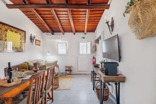 a living room with a table and chairs and a tv at Descanso Alentejano -Casa d'aldeia in Campinho