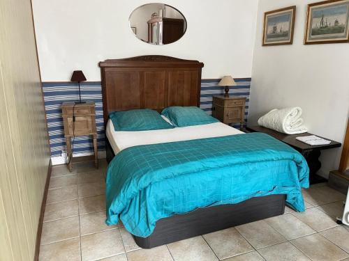 a bedroom with a bed with blue sheets and a mirror at Keranroux 315 - Île de Bréhat in Bréhat