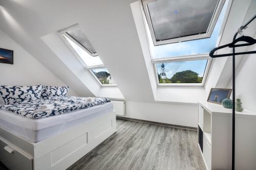 a attic bedroom with a bed and two windows at Altstadtblick Jever in Jever