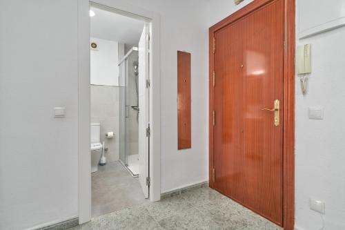 a bathroom with a wooden door and a toilet at Apartamento Familiar Torrox A65 in Torrox