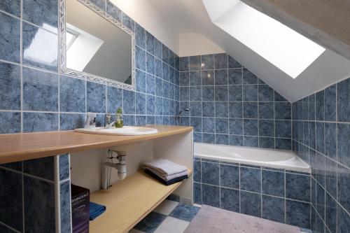 a bathroom with blue tiles and a sink and a tub at Les Hortensias - Gîtes in La Croix-Helléan