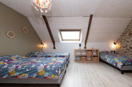 a attic bedroom with two beds and a window at Les Hortensias - Gîtes in La Croix-Helléan